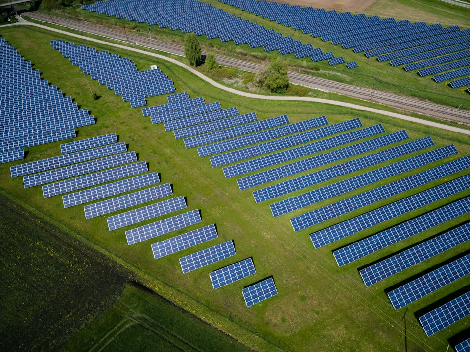 Aerial view of a ground-mounted solar array beside green fields