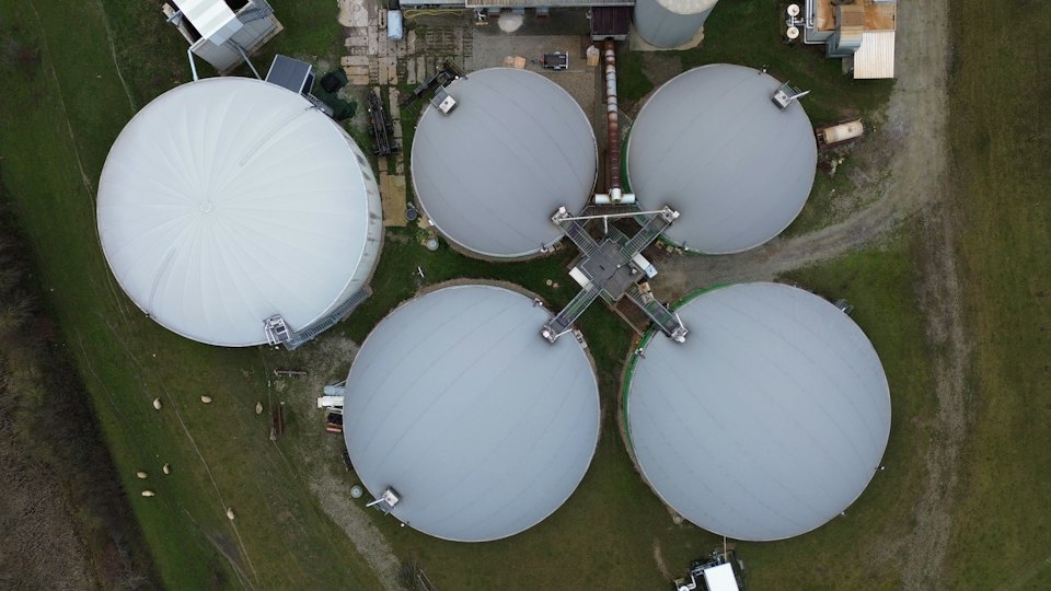 Large white storage tanks in a green field