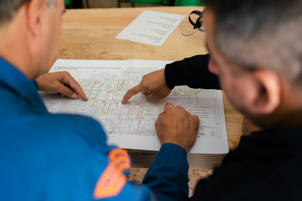 Two engineers reviewing printed plans on a table